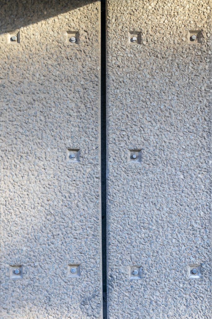 Symmetrical picture of square indentations for bolt heads on a heavily textured concrete fascia